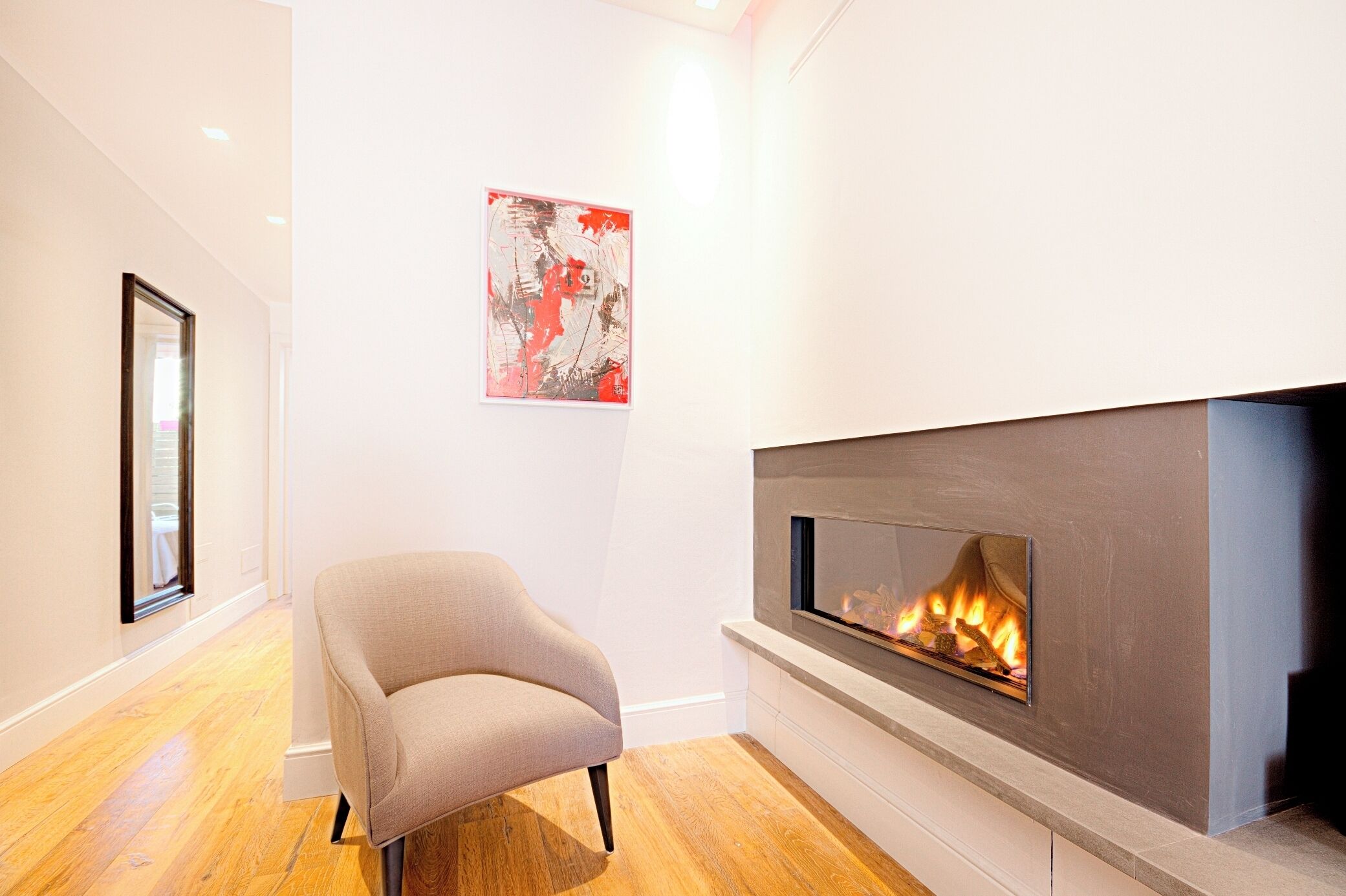 A modern living room with a fireplace, wooden flooring, and a framed artwork on the wall.