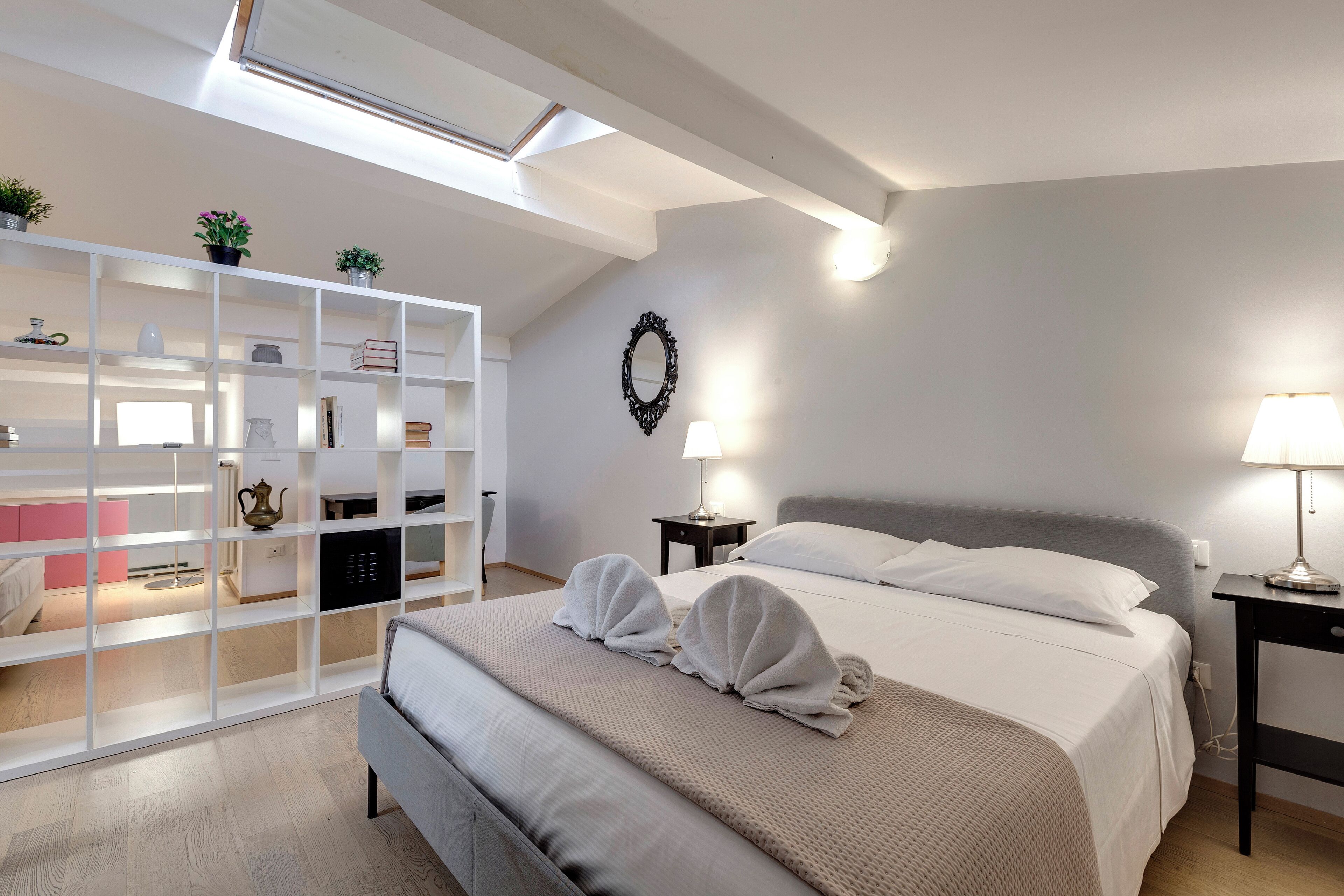 Une chambre bien éclairée, avec un lit, des tables de chevet, une armoire et une lucarne.