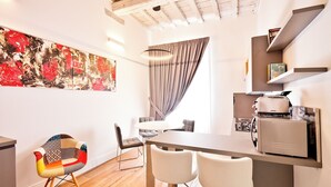 Een moderne keuken met een ingebouwde toaster, een eethoek met een ronde tafel en stoelen, en een groot abstract schilderij aan de muur.