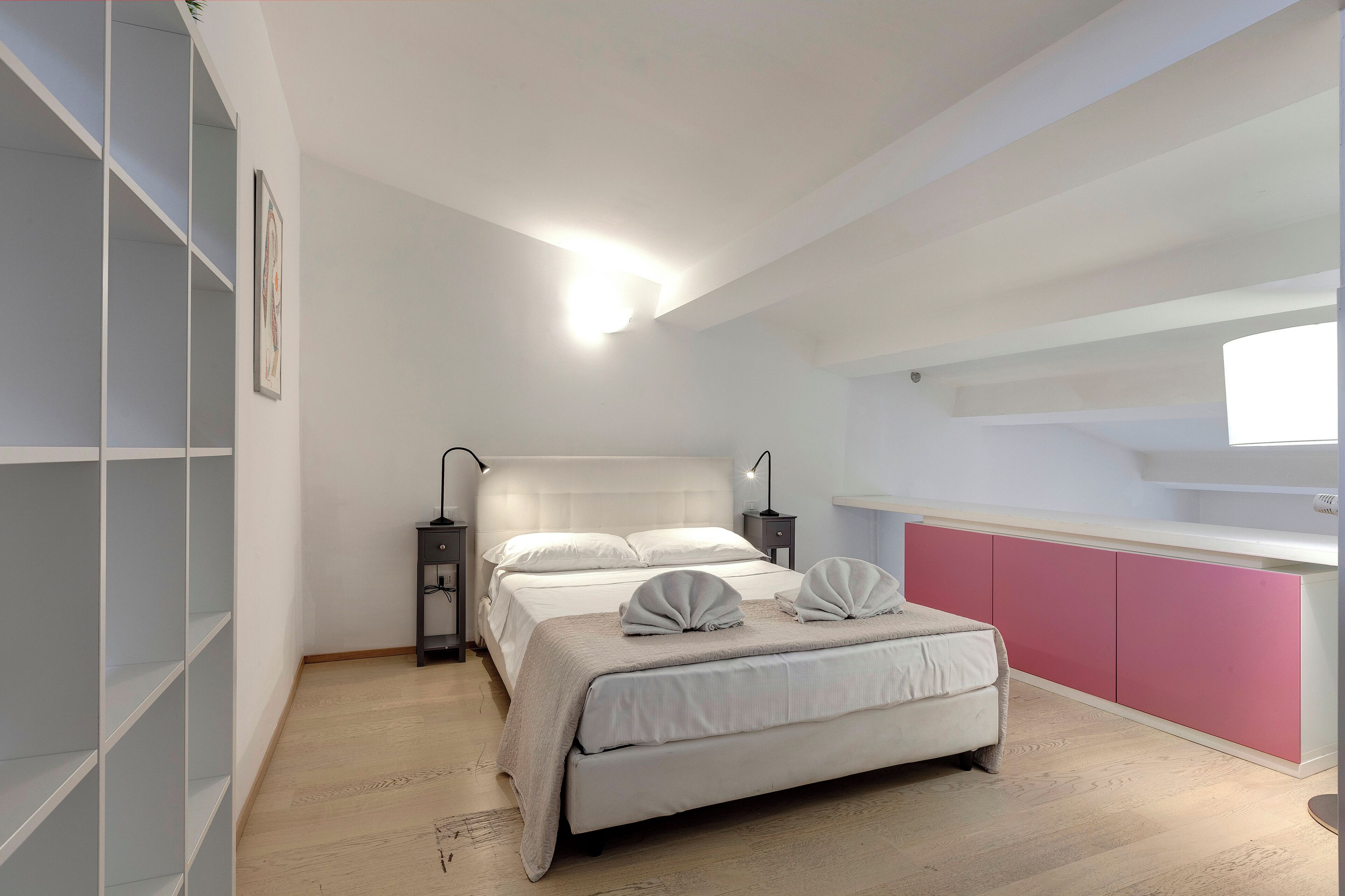 A bedroom with a bed, bedside tables, a wardrobe, and a window.