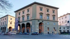 Ein mehrstöckiges Gebäude mit einer symmetrischen Fassade, großen Fenstern und einem zentralen Eingangsbereich mit Vordach.