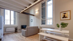 Ein modernes Wohnzimmer mit einer Couch, einer weißen Bank, einem Tisch und einer Topfpflanze.