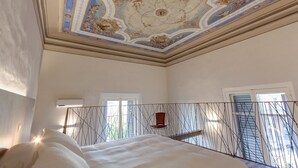 Ein Schlafzimmer mit Bett, Stuhl und Blick ins Freie durch ein Fenster.
