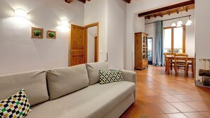 A living room with a sofa, a wooden door, and a dining area with a table and chairs. - Mamo Florence - Zeno Apartment (Florence)