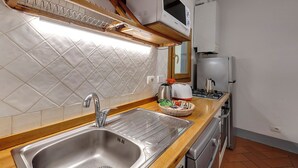 A kitchen with a stainless steel sink, a microwave, and a refrigerator. - Mamo Florence - Zeno Apartment (Florence)
