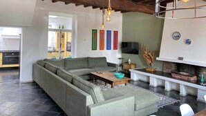 A modern living room with a sectional sofa, a fireplace, and a television. - Authentic house (6p) in prime location near Maastricht (Eijsden)
