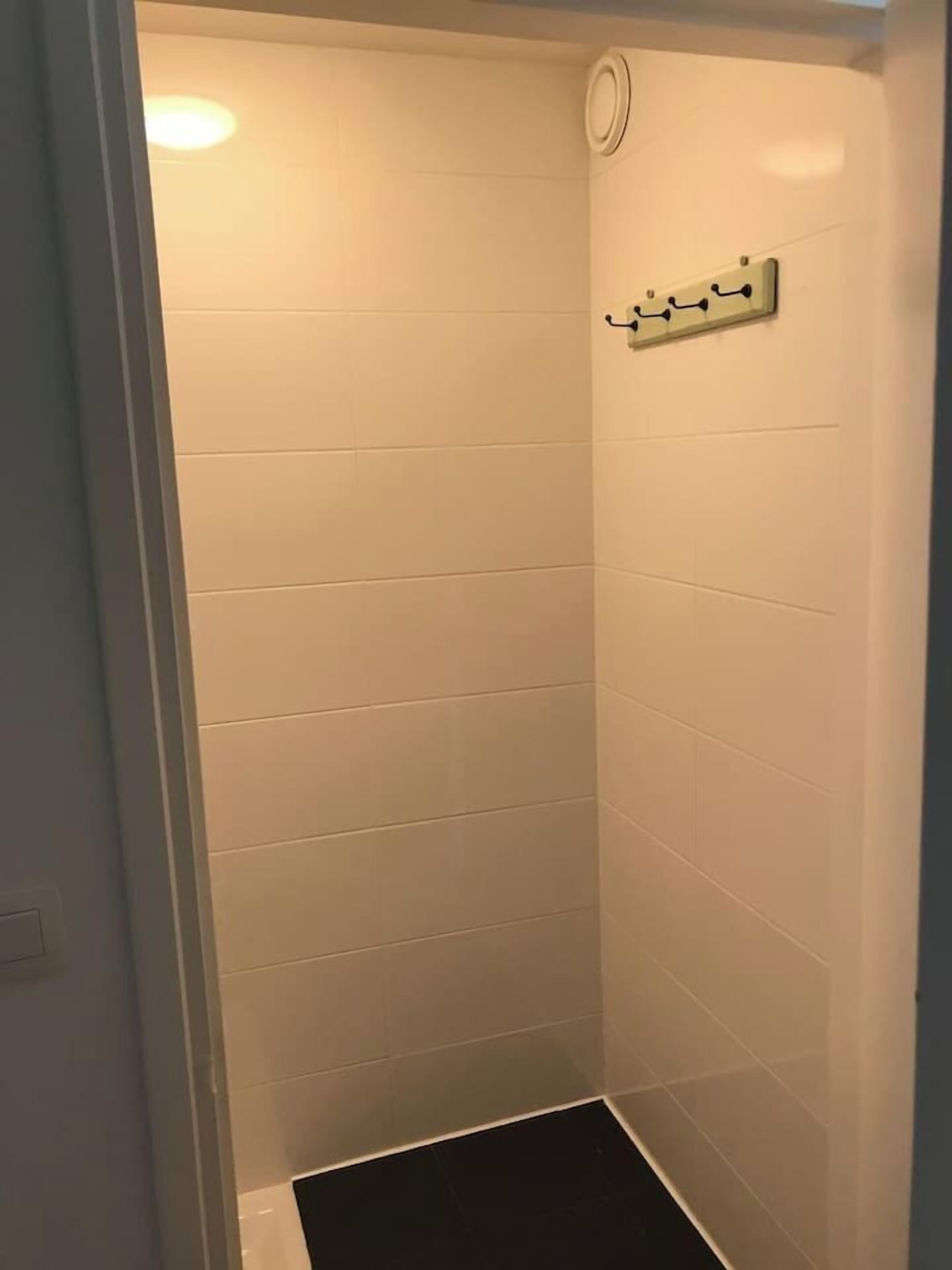 A small, enclosed shower area with white tiled walls and a black floor.