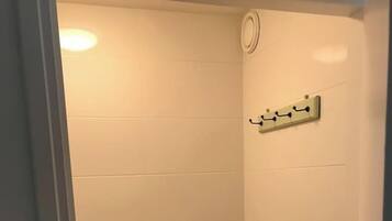 A small, enclosed shower area with white tiled walls and a black floor.