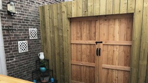 A wooden table and bench, a brick wall, and a wooden door with a handle. - Authentic house (6p) in prime location near Maastricht (Eijsden)