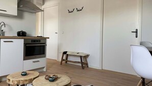 A modern kitchen with a stove, oven, and cabinets. There is a small wooden table with pottery and a bench with a fur throw. - Cozy apartment (4p) prime location near Maastricht (Eijsden)
