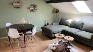 A loft-style living space with a dining area, a sofa, a cowhide rug, and a skylight. - Cozy apartment (4p) prime location near Maastricht (Eijsden)