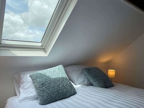 A bedroom with a skylight, a bed with white bedding, two pillows, and a bedside lamp. - Cozy apartment (4p) prime location near Maastricht (Eijsden)