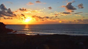 Ein Sonnenuntergang über dem Meer mit einer felsigen Küstenlinie.