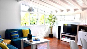 Ein Wohnzimmer mit einer Couch, einem Couchtisch, einem Fernseher und einer Topfpflanze.
