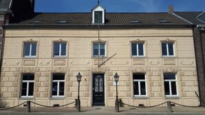 A historic building with a symmetrical facade, a central entrance with a decorative door, and evenly spaced windows. - Authentic cozy group stay (7p) near Maastricht (Eijsden)