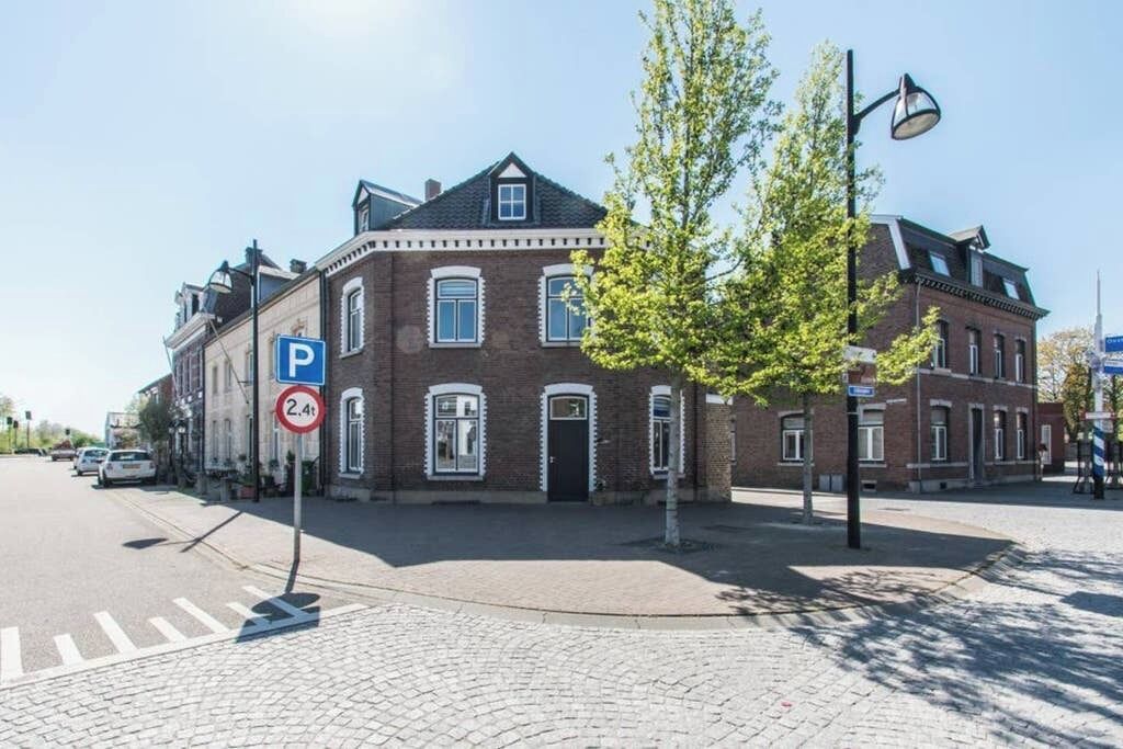 A street corner with a brick building, a parking sign, and a tree.