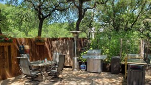 Un patio al aire libre con una parrilla, zona de estar y un tanque de gas.