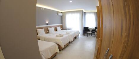 A hotel room with three beds, a desk, and a chair.
