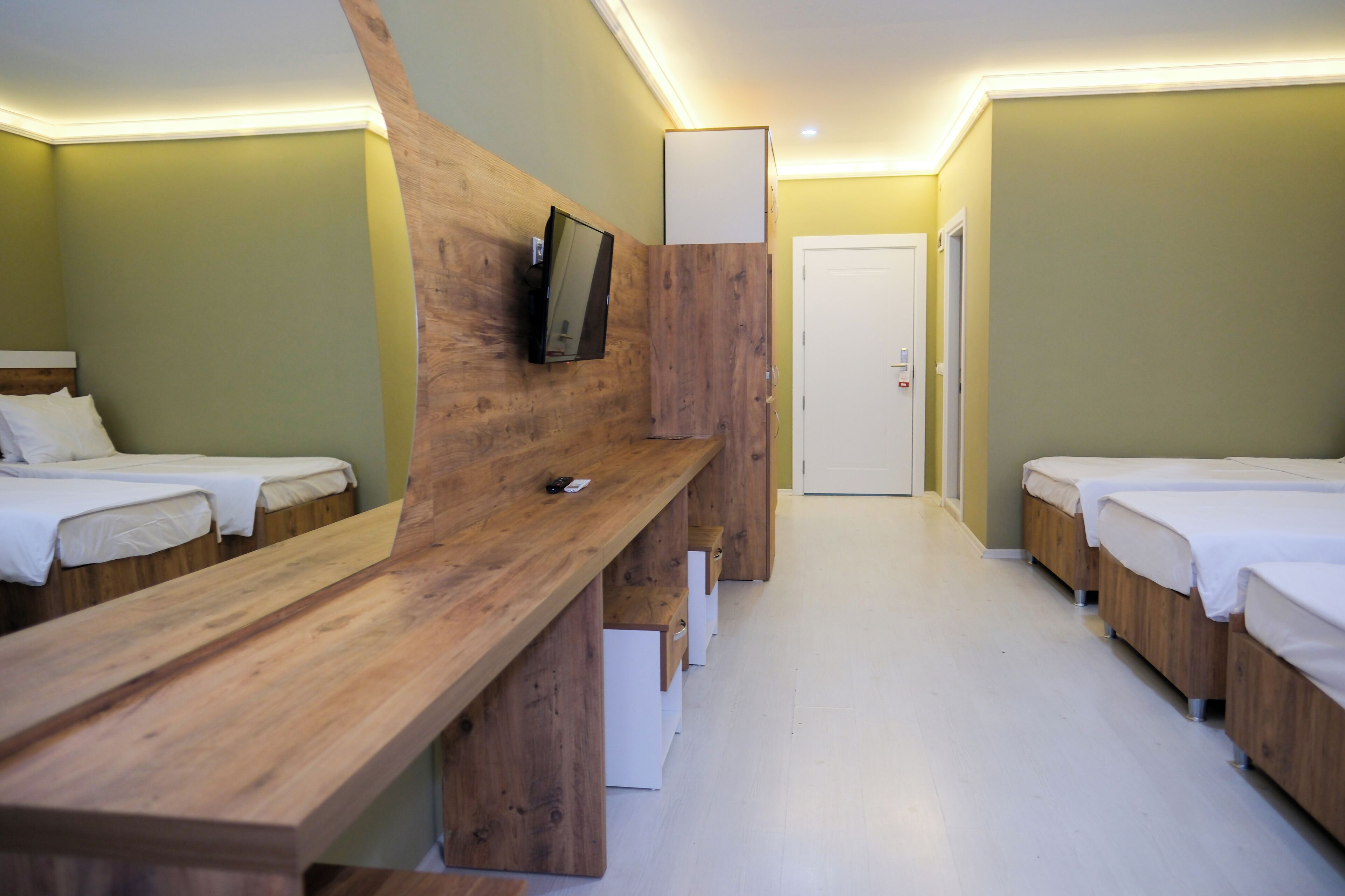 A hotel room with wooden furniture, a television mounted on the wall, and a door in the background.