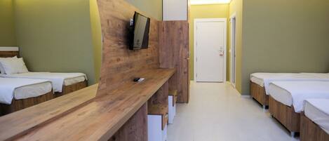 A hotel room with wooden furniture, a television mounted on the wall, and a door in the background.