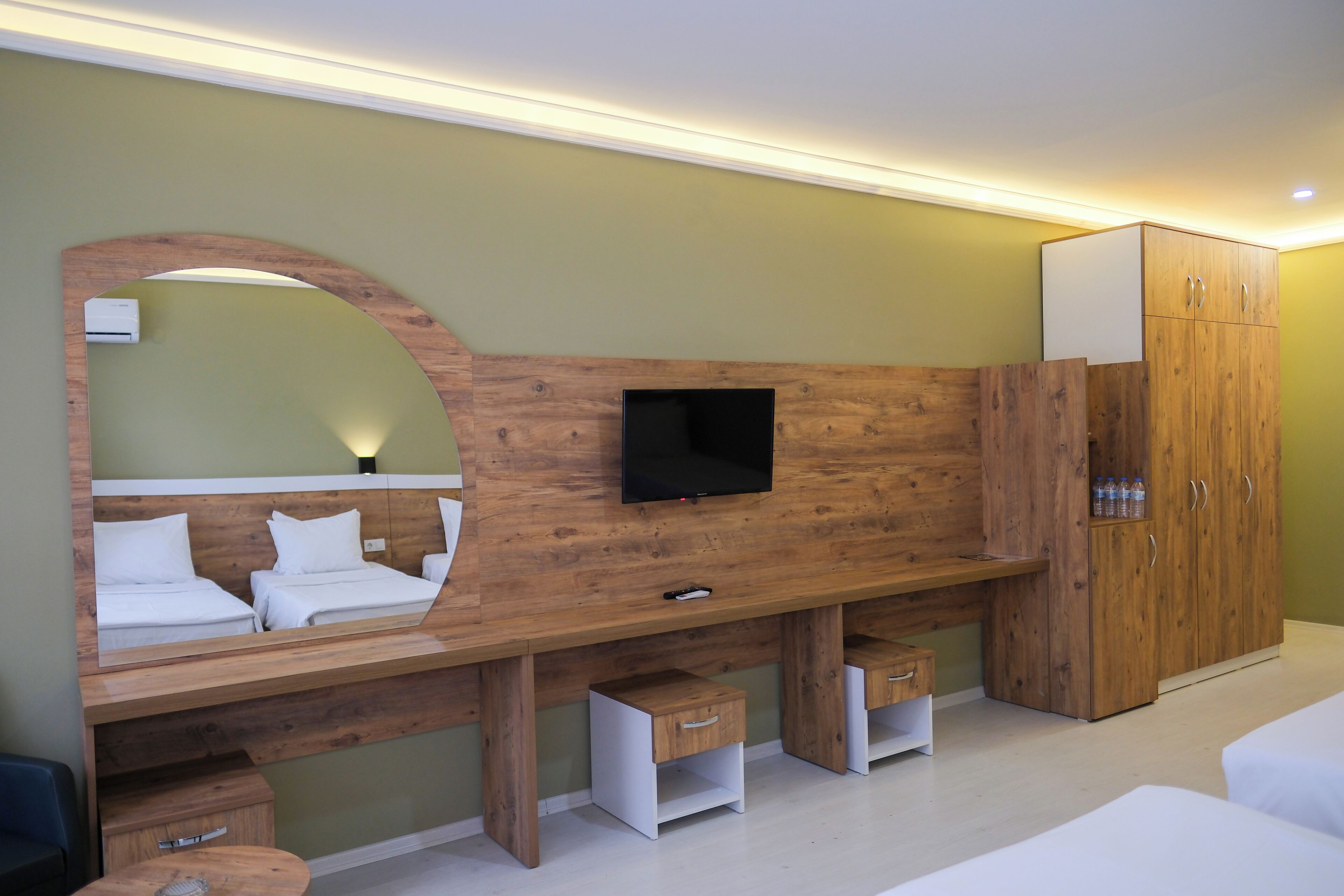 Ein modernes Hotelzimmer mit einer Wandverkleidung aus Holz, einem Flachbildfernseher, einem Kleiderschrank und einem großen Spiegel.