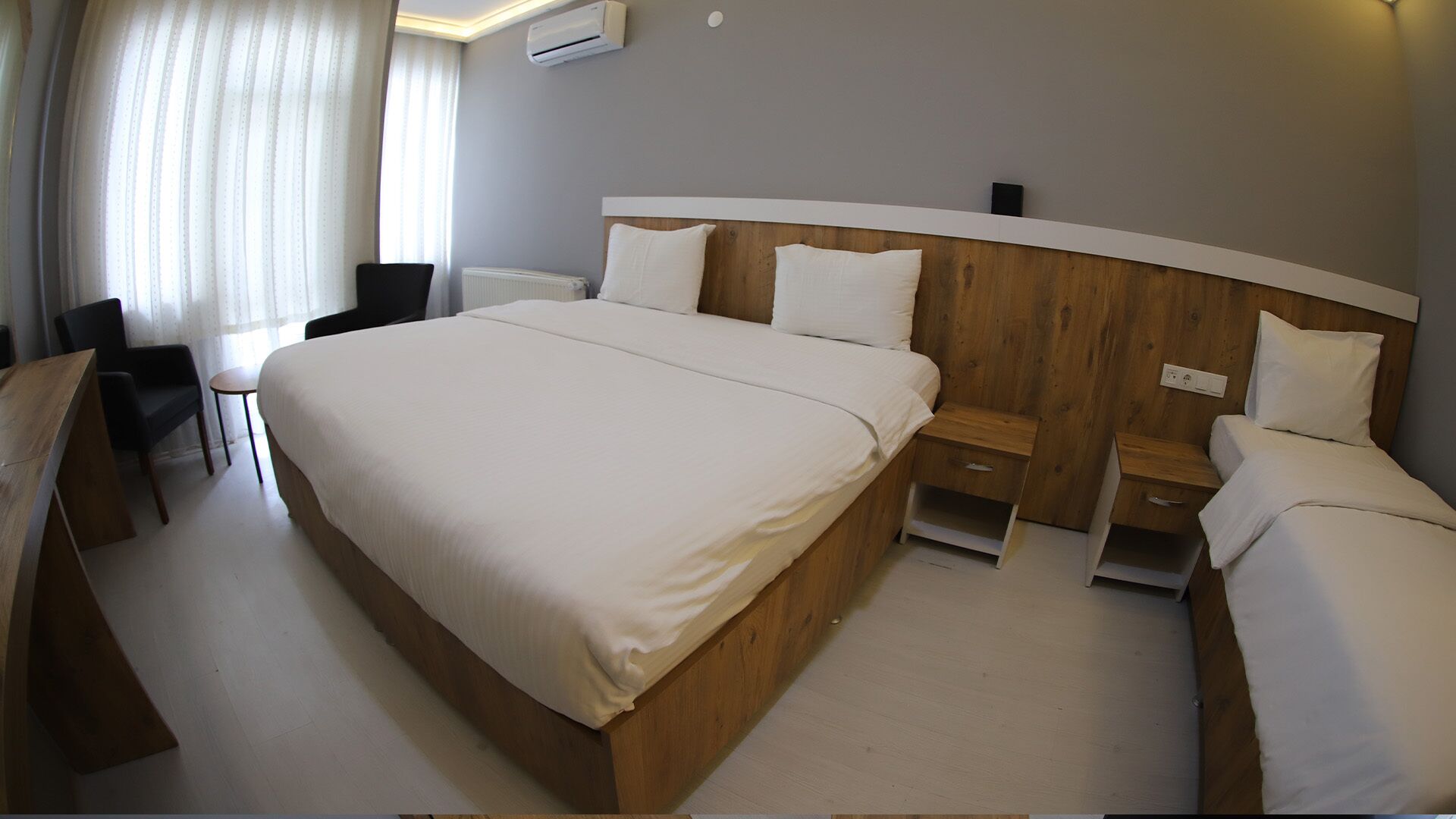 A hotel room with a large bed, two bedside tables, a desk, and a chair.