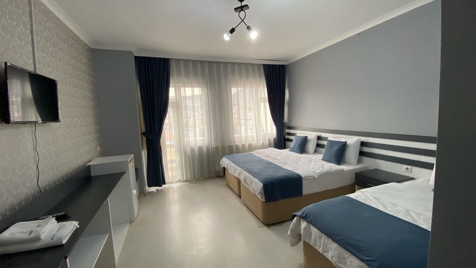 Een hotelkamer met twee bedden, een bureau, een televisie en een raam met gordijnen.