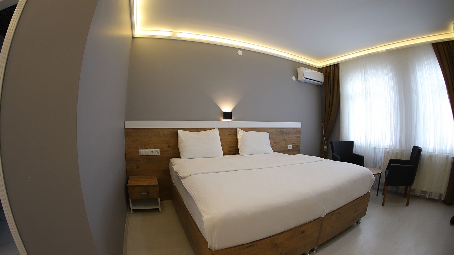 Una habitación de hotel moderna con una cama grande, mesitas de noche, un escritorio y una silla.