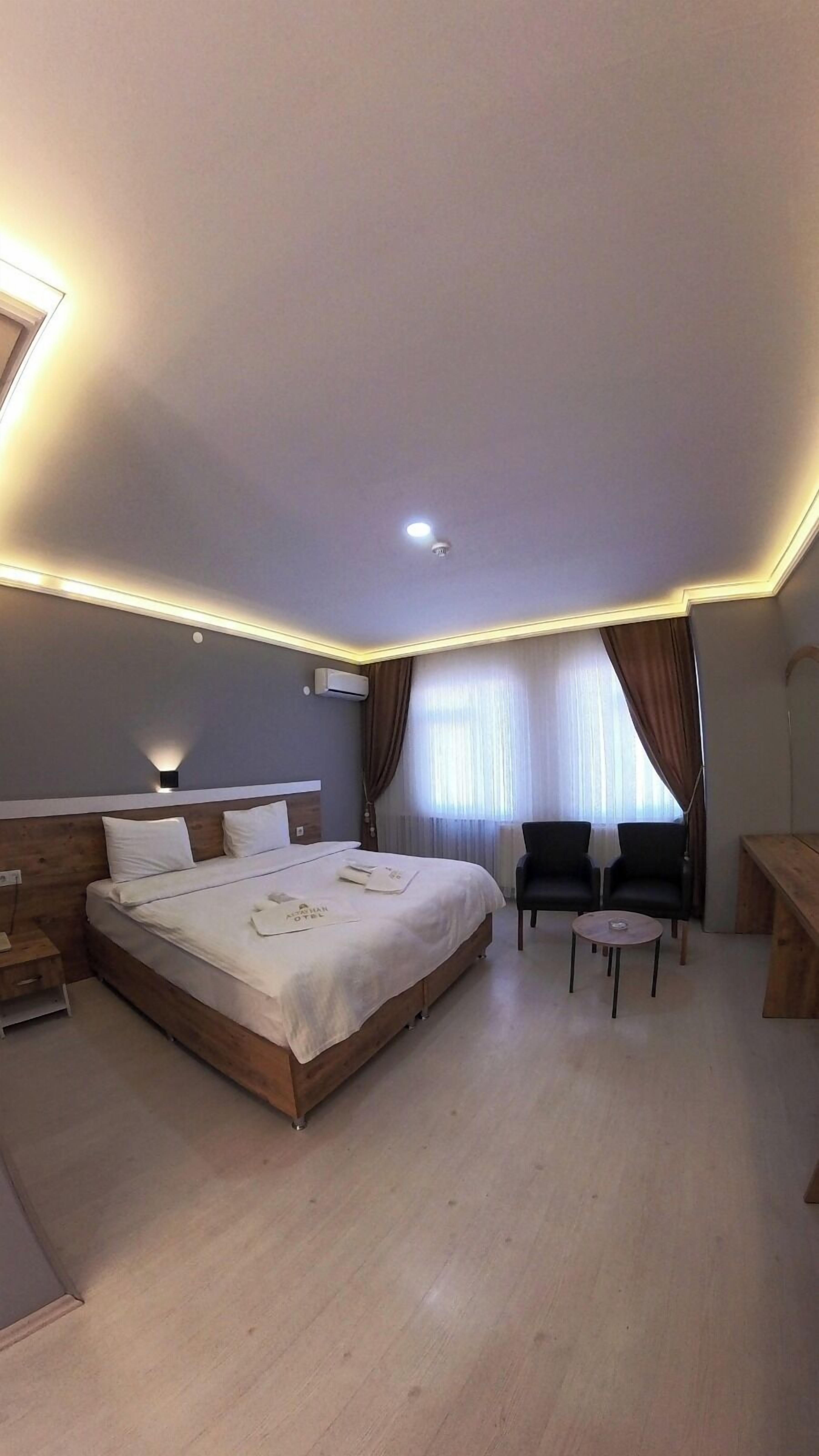 Una habitación de hotel moderna con una cama grande, un escritorio, dos sillas y una mesita.
