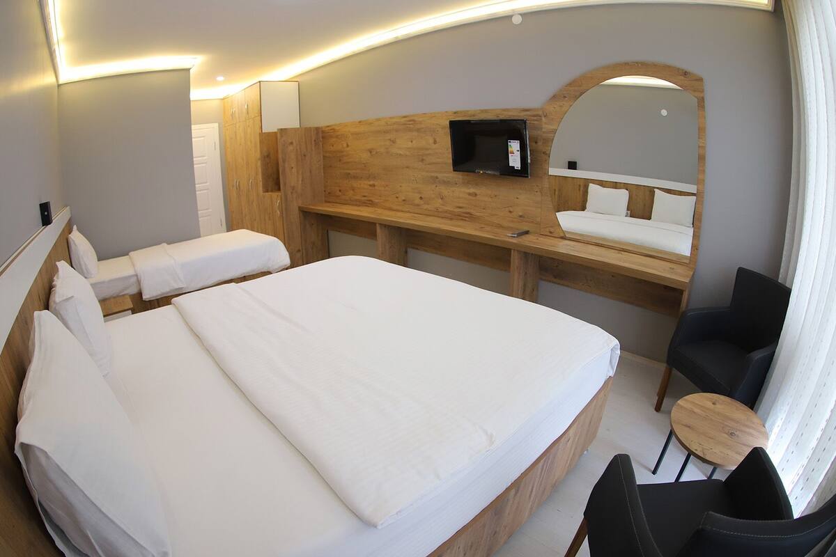 Una habitación de hotel con una cama grande, un escritorio con una silla, un televisor y un espejo.