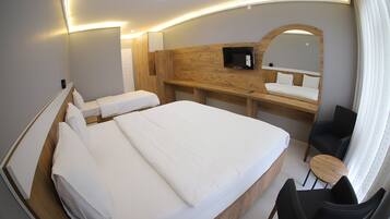 A hotel room with a large bed, a desk with a chair, a TV, and a mirror.