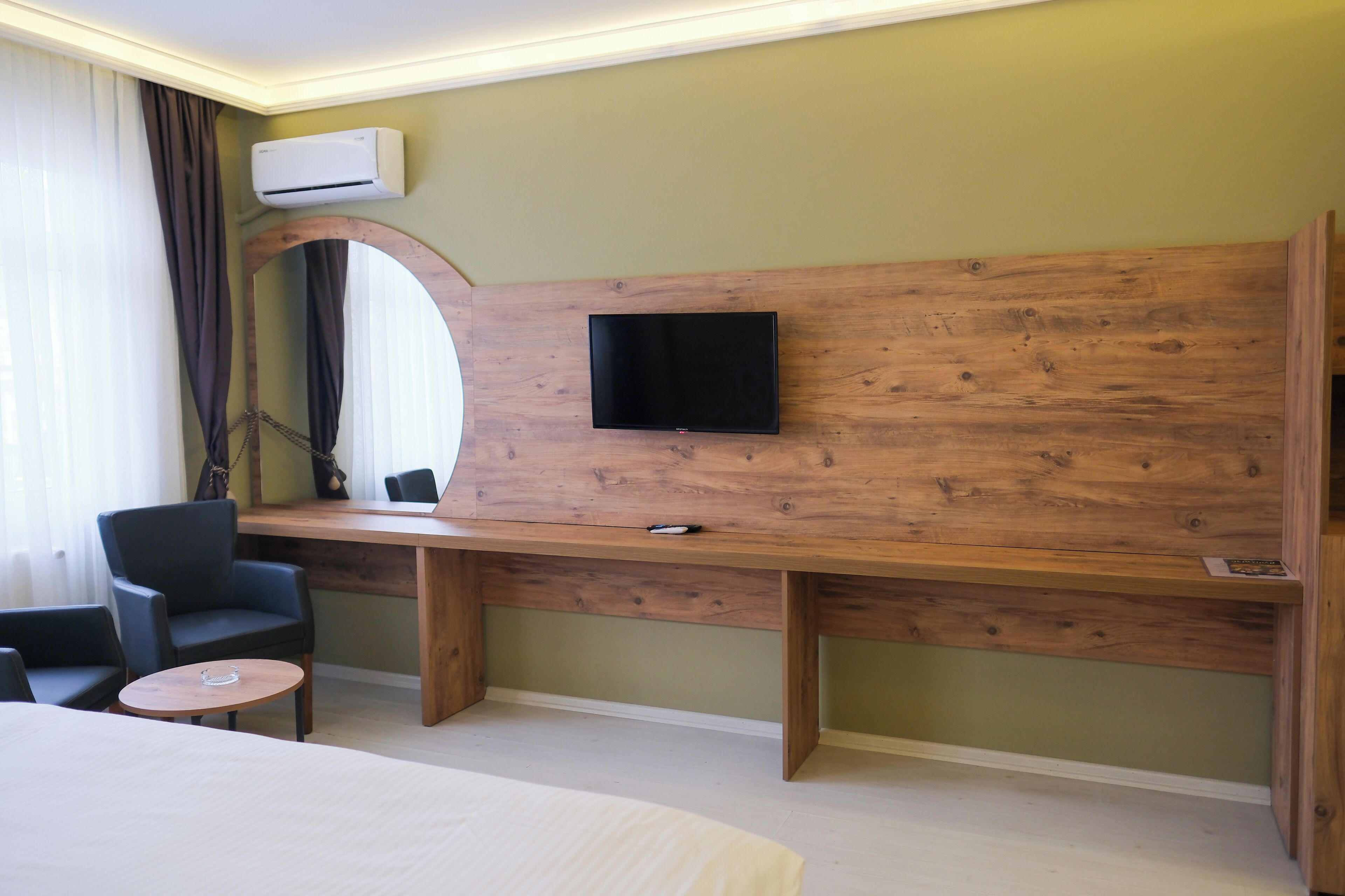 Hotelkamer met een houten bureau, een flatscreen televisie aan de wand, een bed en een zithoek met stoelen.