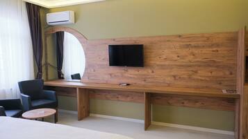 Hotelkamer met een houten bureau, een flatscreen televisie aan de wand, een bed en een zithoek met stoelen.