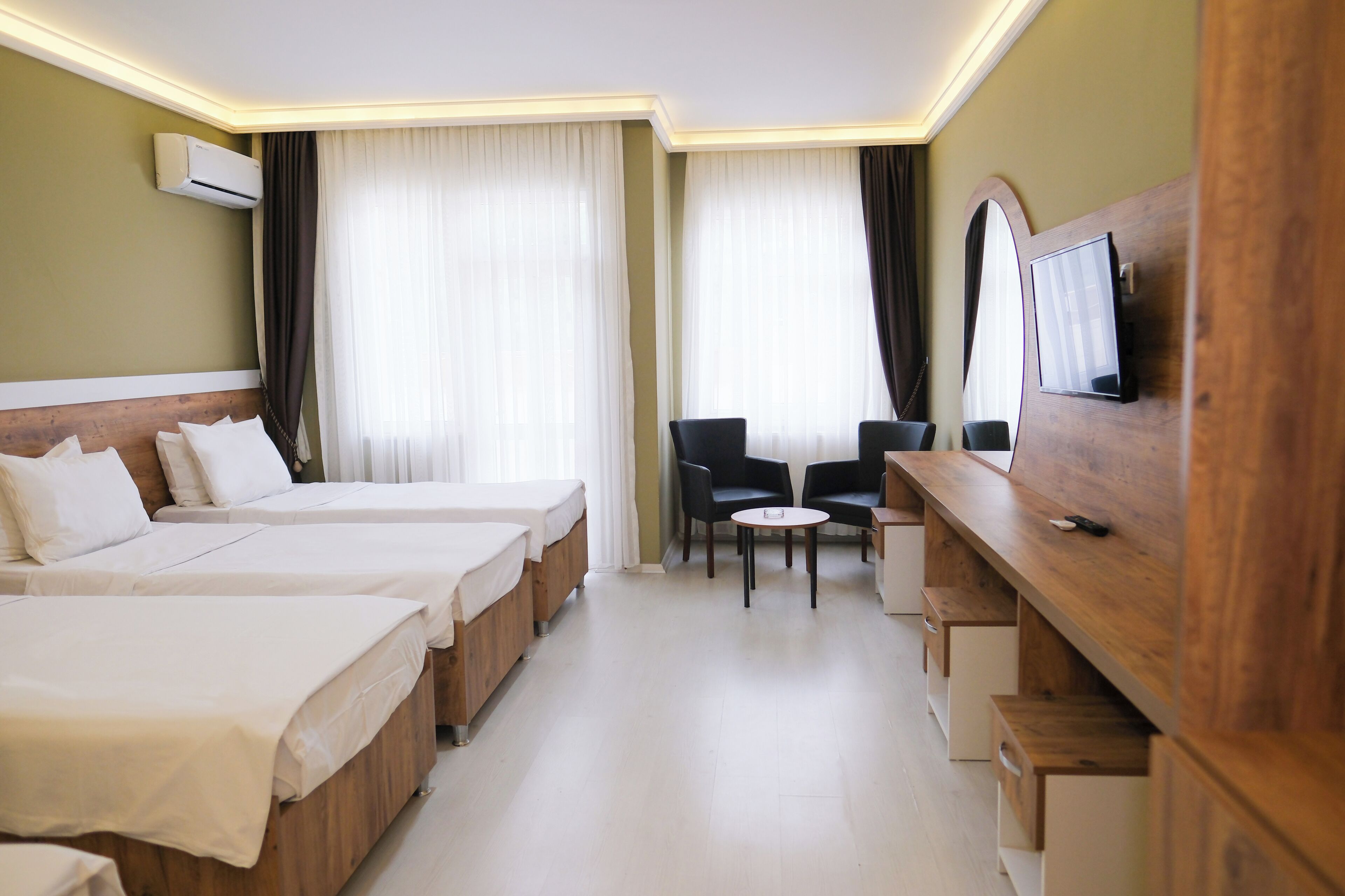 Habitación de hotel con dos camas, un escritorio, una silla y un televisor montado en la pared.