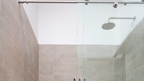 A modern shower area with a glass enclosure, a handheld showerhead, and a tiled floor.