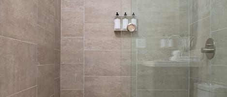 A modern shower area with a glass enclosure, a handheld showerhead, and a tiled floor.
