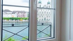 A window with a view of a water body and buildings with domed roofs. - Hitrental Chapel Bridge Apartments (Lucerne)