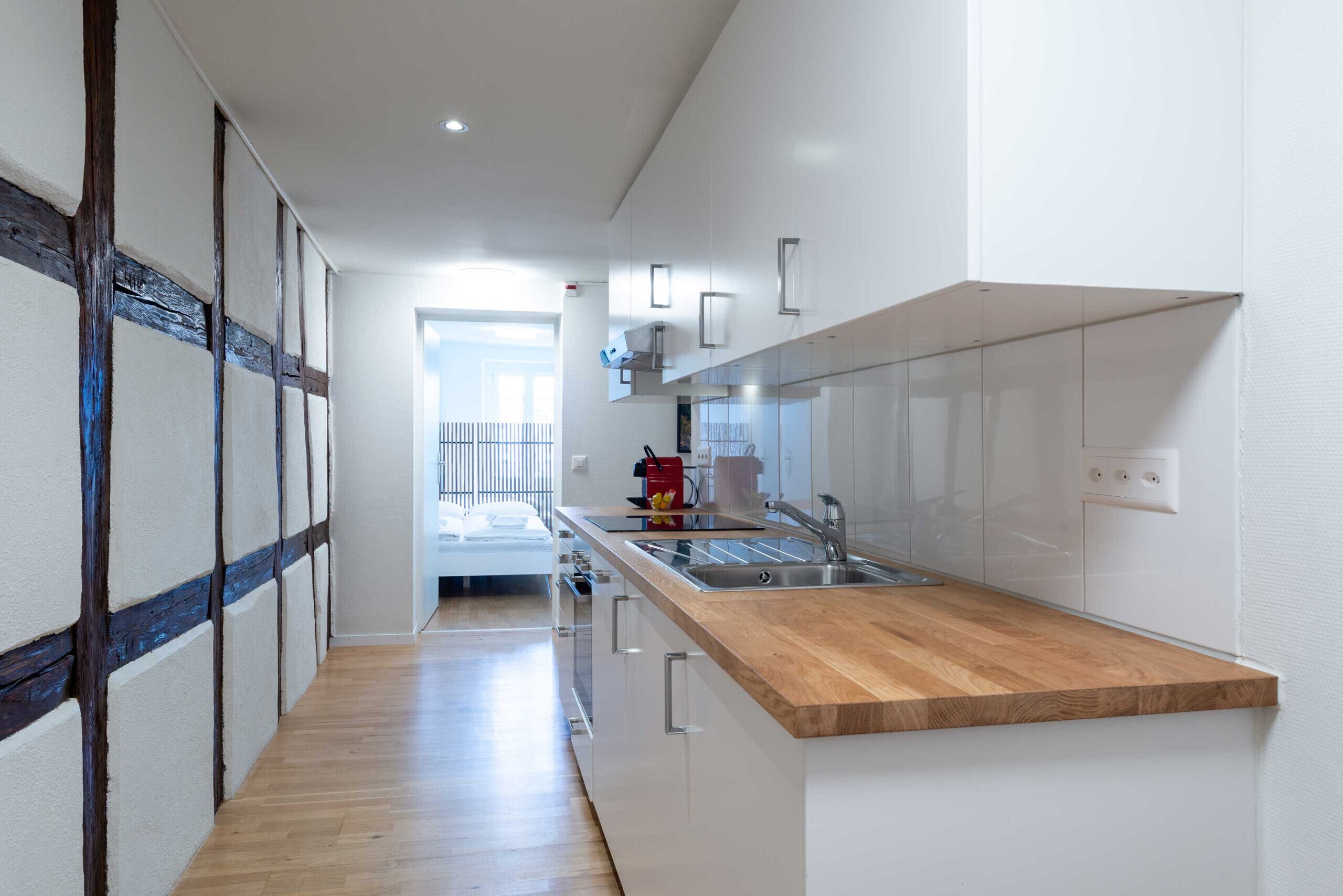 Een moderne keuken met een houten aanrecht, witte kastjes en uitzicht naar buiten.