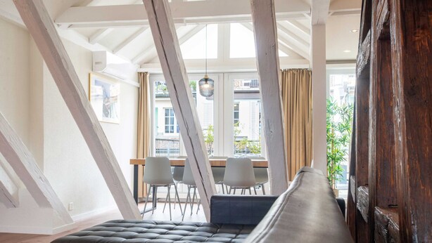 A modern interior with a bench, dining area, and large windows. - Hitrental Chapel Bridge Apartments (Lucerne)