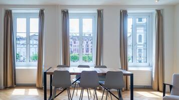 Ein Konferenzraum mit einem großen Tisch, sechs Stühlen und drei fensterbepflanzten Fenstern.