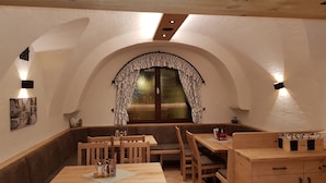 Un comedor acogedor con muebles de madera, un amplio ventanal arqueado con cortinas estampadas e iluminación empotrada.