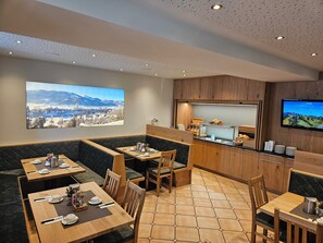 A restaurant with a mountain view, wooden furniture, and a buffet area.