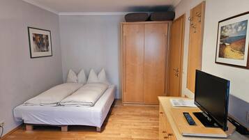Une chambre à coucher avec un lit, une armoire en bois et un téléviseur posé sur un bureau en bois.