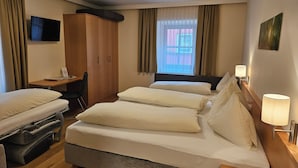 Una habitación de hotel con cama, escritorio, silla, armario y televisor.