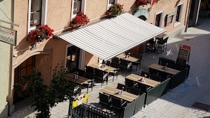 Un edificio con techo de tejas, zona de estar al aire libre y macetas con flores.