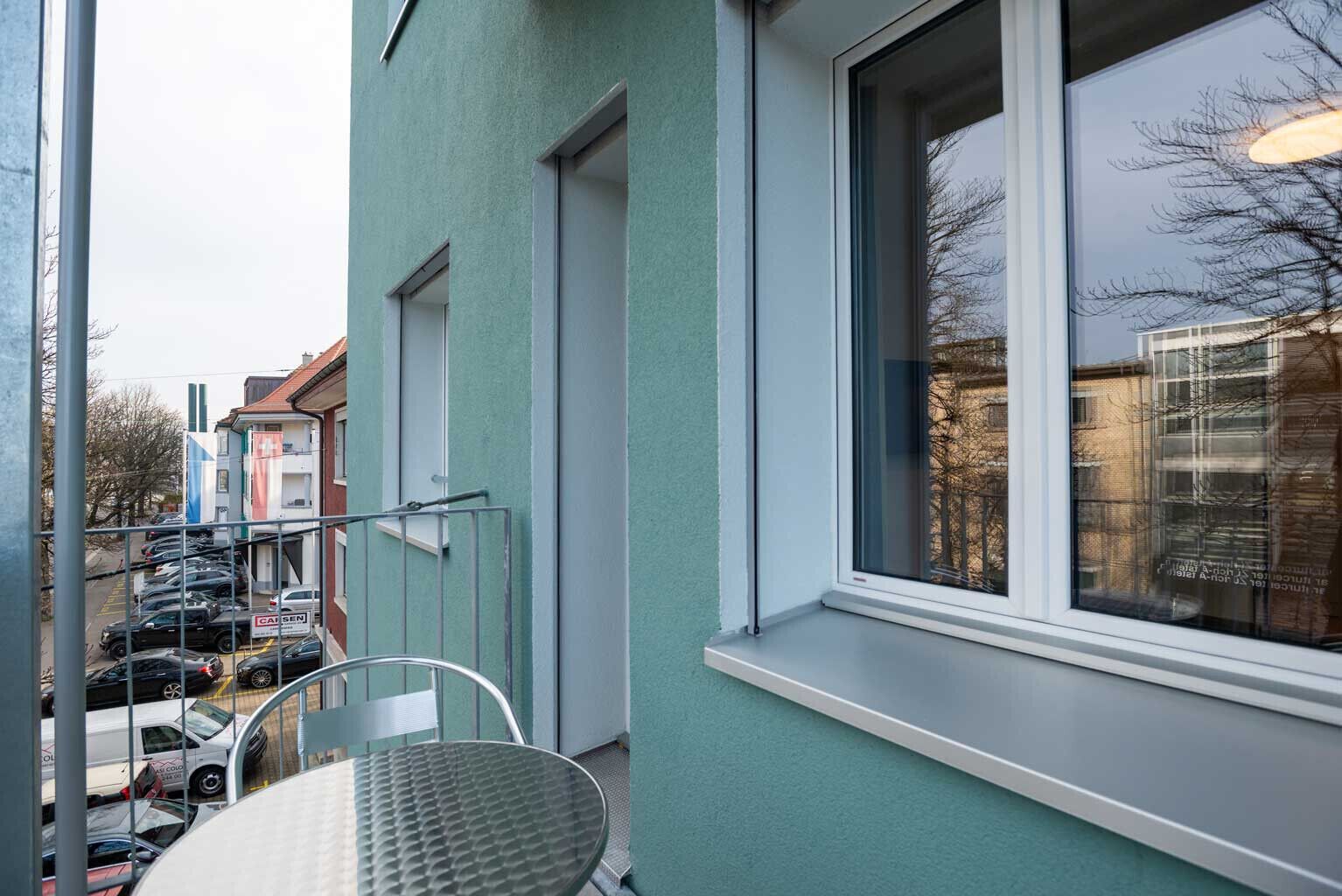 A balcony with a metal railing, a table, and chairs.