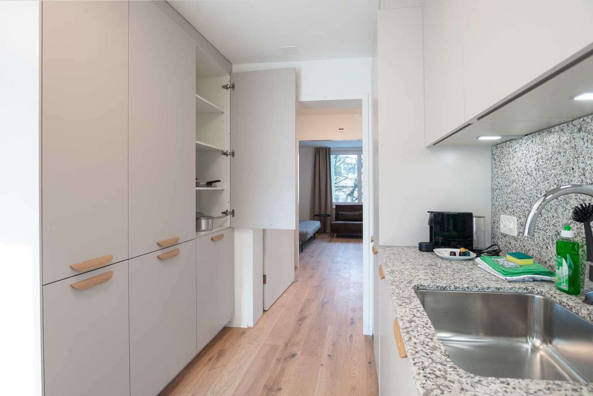 Una cocina moderna con encimera de granito, pileta de acero inoxidable y comedor con mesa y sillas.