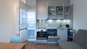 Une cuisine compacte dotée d’appareils électroménagers intégrés, d’un plan de travail et d’un coin repas.