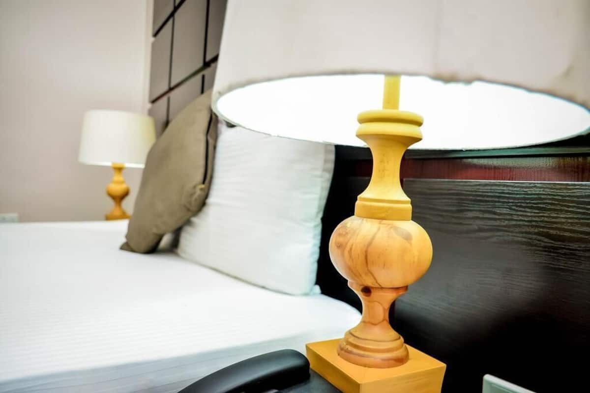 A neatly made bed with a white comforter and a wooden headboard.