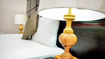 A neatly made bed with a white comforter and a wooden headboard.